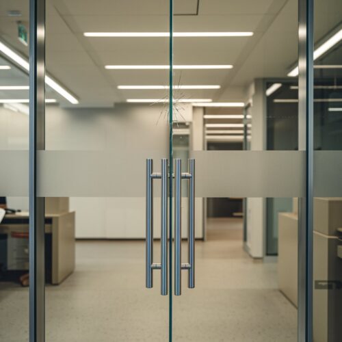 Kopfhohe, geschlossene Glastür mit leichtem Schmutz und feinem Riss in modernem Bankinterieur in Regensburg.